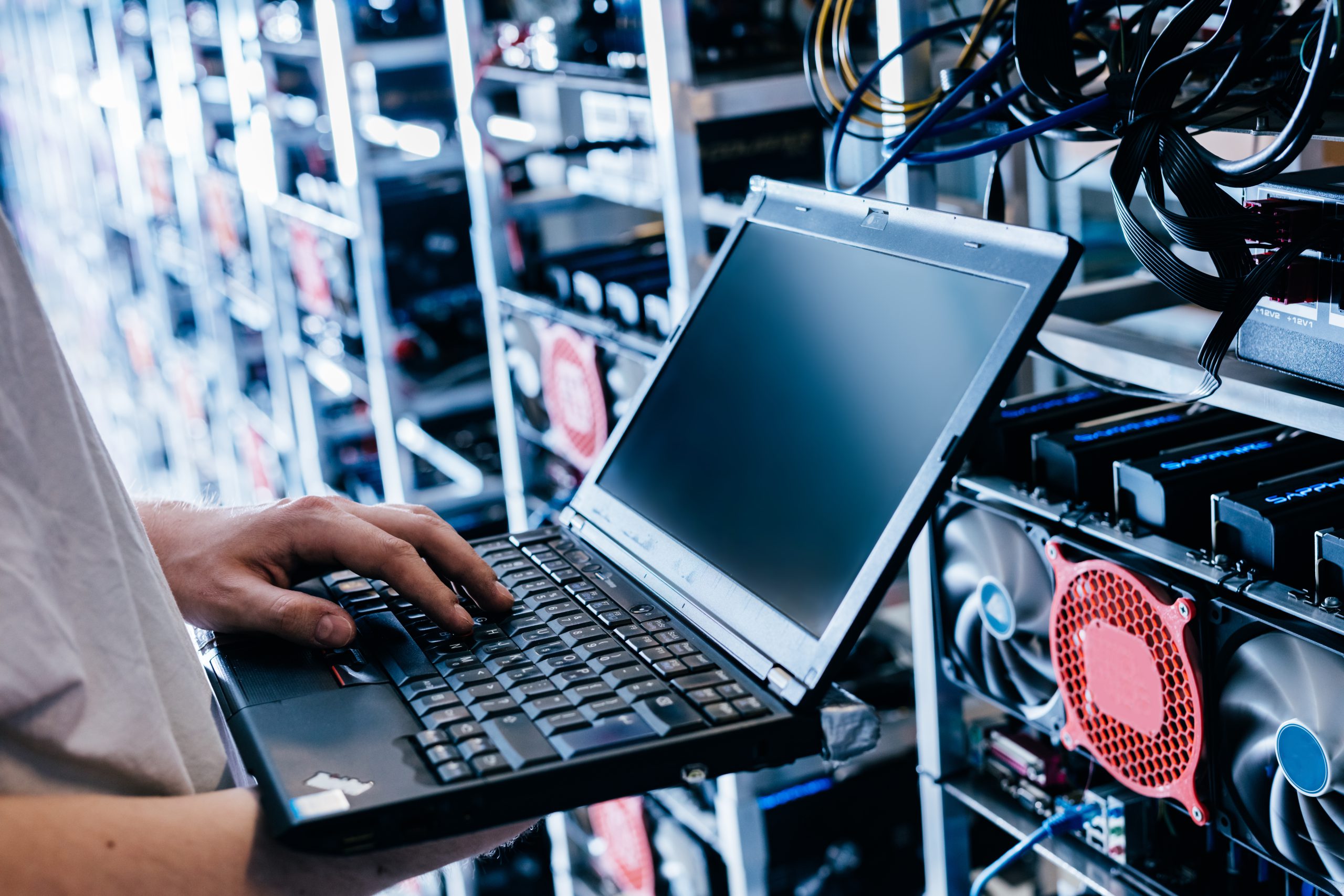 IT specialist working on computer in bitcoin and crypto currency mining farm. Big data center. High tech server computers at work